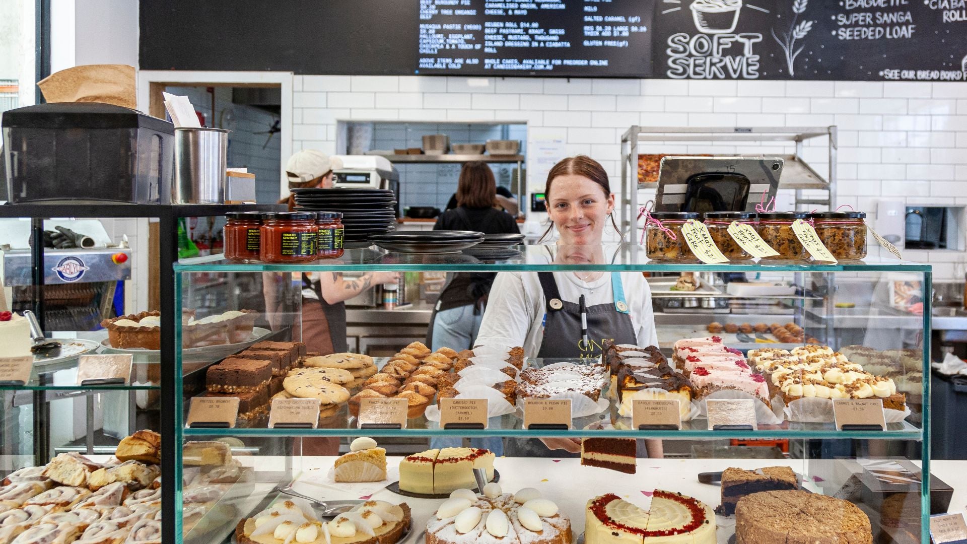 Candied Bakery counter with various pasties and staff member behind the counter.